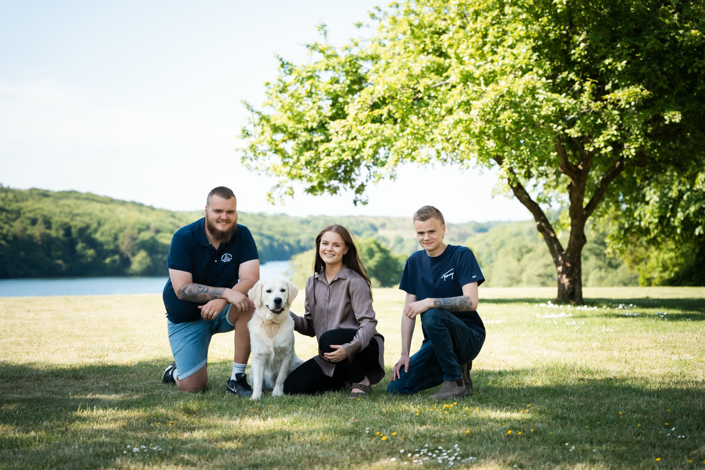 Familie med hund på græsset ved søen