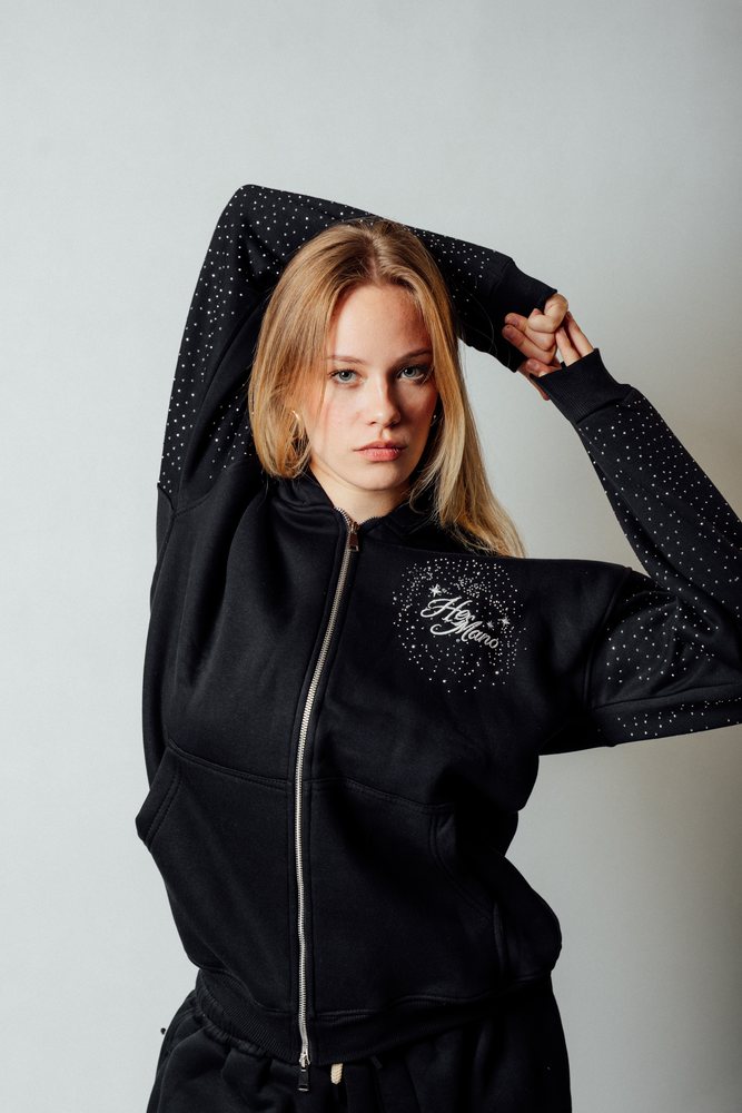 Model i sort zip-hættetrøje med glitrende sten på ærmerne
